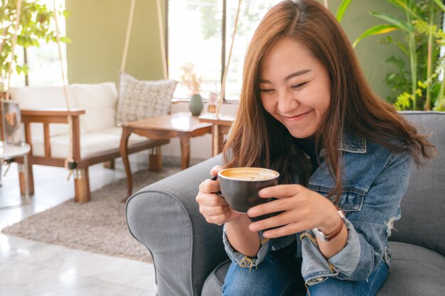 belle femme asiatique tenant et boire du café chaud avec un sentiment de bonheur au café