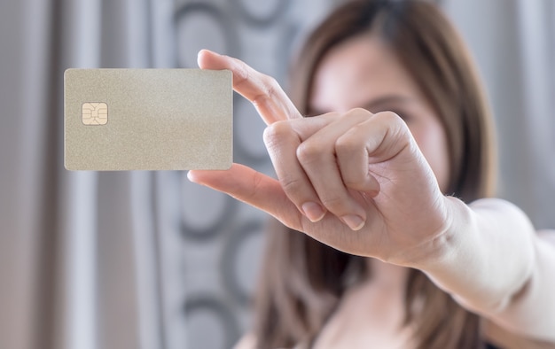 Belle femme asiatique tenant une carte de crédit vierge doré