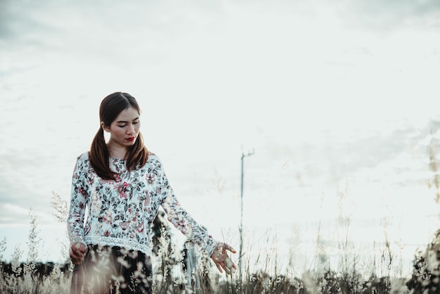 Belle femme asiatique tenant une fleur d'herbe dans le champ le soir les gens de la Thaïlande