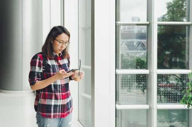 Une belle femme asiatique utilise un smartphone dans le centre-ville pour rechercher divers