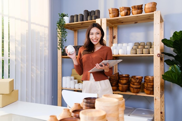 Belle femme asiatique vendant des produits de vase faits à la main en ligne en direct à la maison
