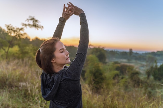 Belle femme asiatique en veste sombre étirant ses bras pendant sa pause de son exercice du matin