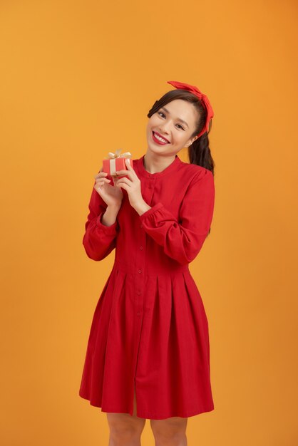 Belle femme asiatique vêtue d'une robe rouge et debout sur un fond orange