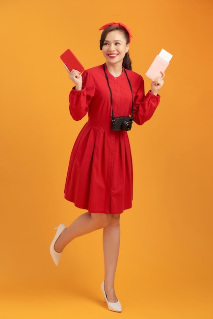 Belle femme asiatique vêtue d'une robe rouge et debout sur un fond orange
