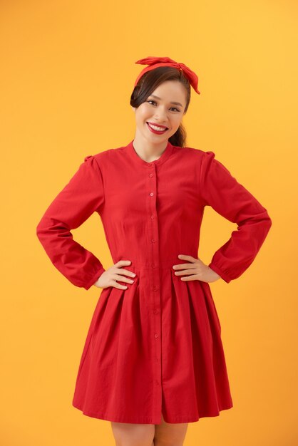 Belle femme asiatique vêtue d'une robe rouge et debout sur un fond orange