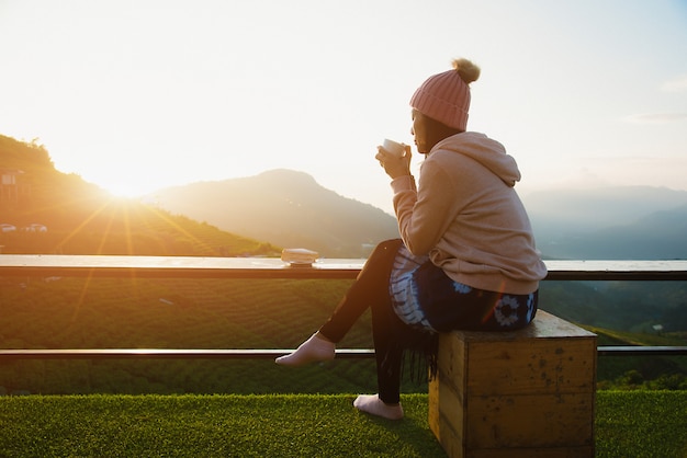 Une belle femme assise et boire du café le matin avec une montagne