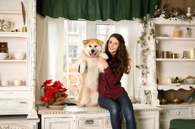 Belle femme assise commode arbre rétro. câlins, câlins avec son chien akita inu.