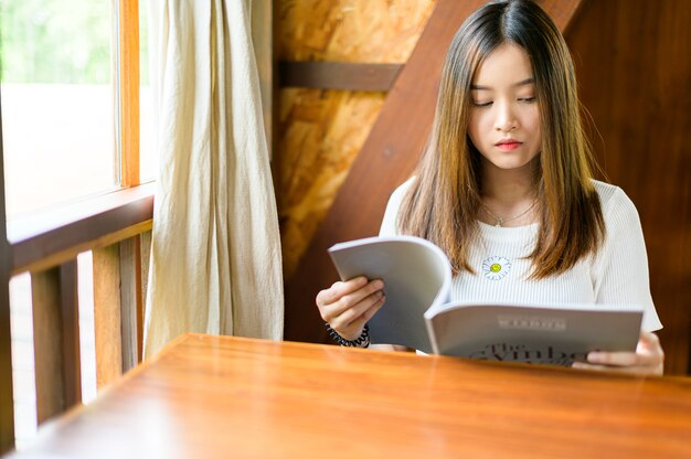 Belle femme assise dans un café en lisant un magazine