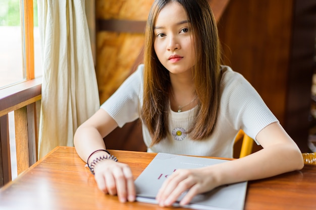 Belle femme assise dans un café en lisant un magazine