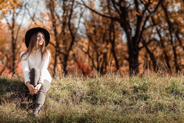 Belle femme assise sur l'herbe le jour d'automne ensoleillé