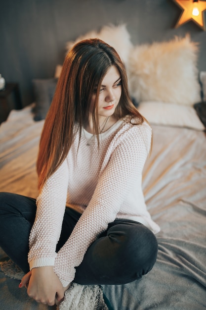 Belle femme assise sur le lit à la maison