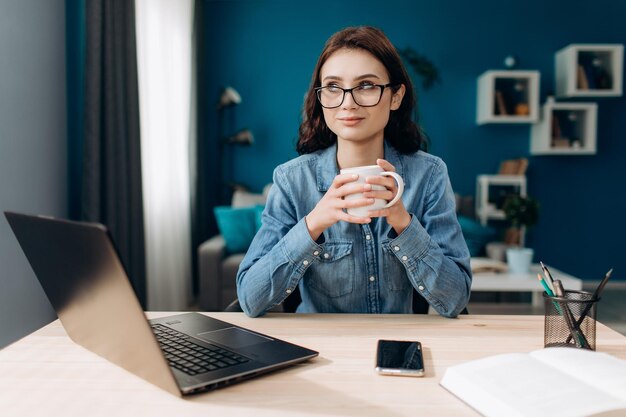 Photo belle femme assise à table avec café et ordinateur portable