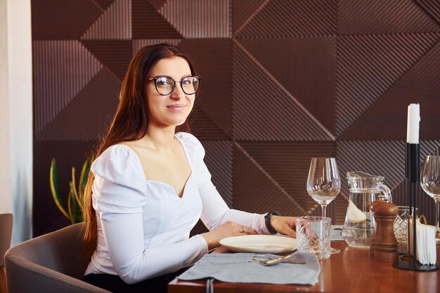 Belle femme assise à table à l'intérieur du nouveau restaurant de luxe moderne