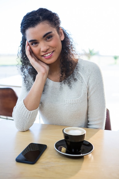 Belle femme assise avec une tasse de café sur la table