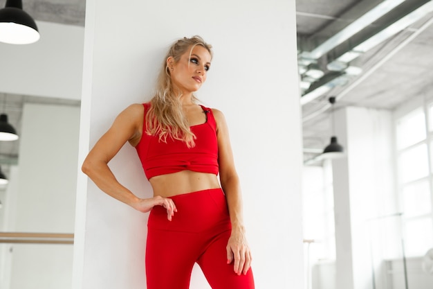 belle femme athlétique en costume rouge faisant du yoga dans la salle de gym