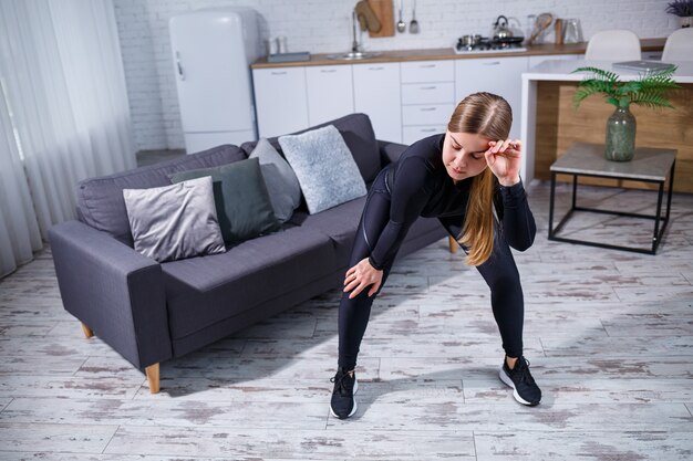 Belle femme athlétique en haut noir et leggings faisant du sport à la maison. Motivation à faire du sport. Mode de vie sain.