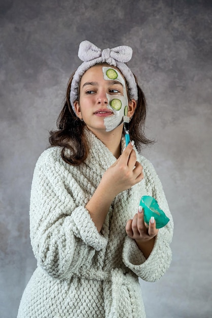 Une belle femme attrayante appliquant un masque blanc d'argile au visage tenant un pinceau Procédure de soins de la peau par aromathérapie Spa