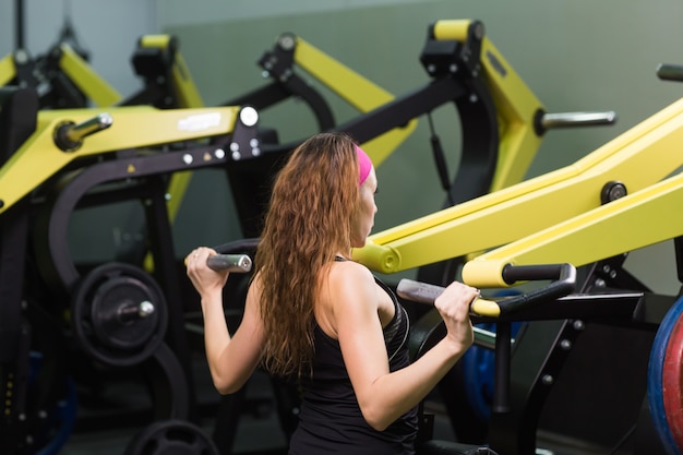 Belle femme au gymnase exerçant sur une machine.