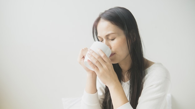 Belle femme au lit avec une tasse de café