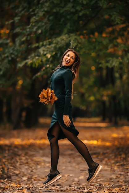 Belle femme en automne parc sautant et souriant - journée ensoleillée