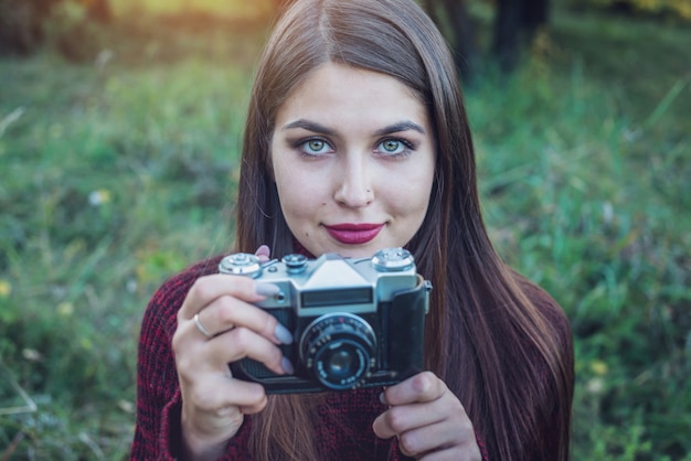 Belle femme en automne Park détient une caméra rétro vintage