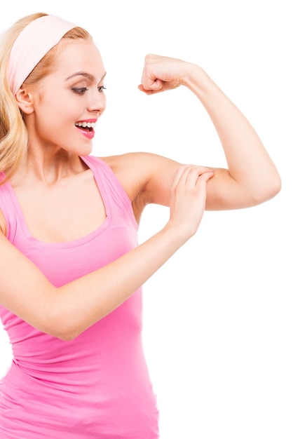 Belle femme aux cheveux blonds pin-up en chemise rose touchant son biceps