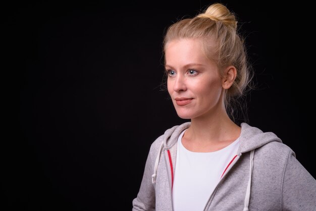 Belle femme aux cheveux blonds prêt pour la salle de sport contre le mur noir