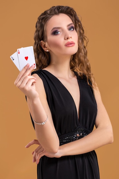 Belle femme aux cheveux bruns tenant deux as comme signe pour le jeu de poker, le jeu et le casino