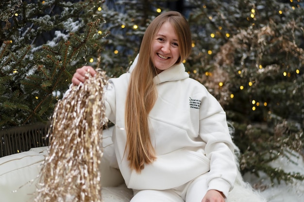 Photo belle femme aux cheveux longs et en costume d'hiver se promène parmi les sapins