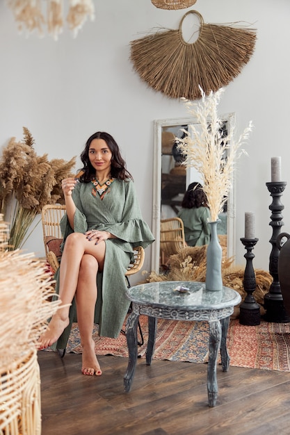 Belle femme aux cheveux noirs en tenue ethnique chamanique dans la chambre décorée de style bali