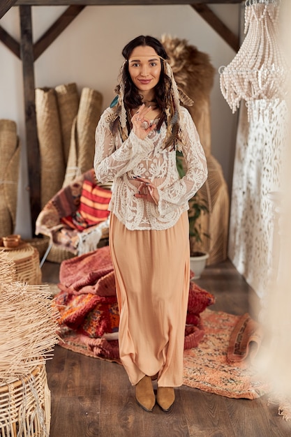 Belle femme aux cheveux noirs en tenue ethnique chamanique dans la chambre décorée de style bali