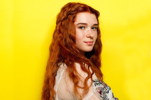 Belle femme aux cheveux roux ondulés sur fond jaune