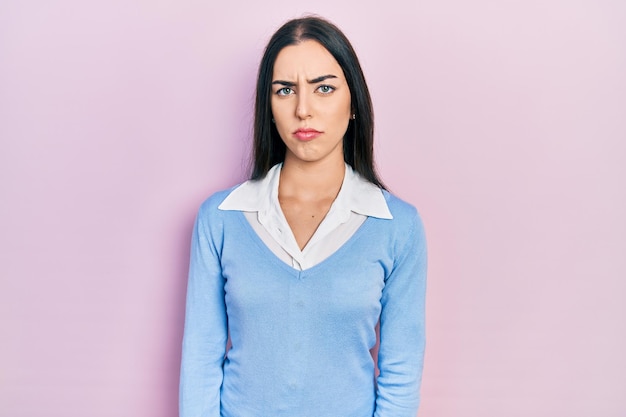 Belle femme aux yeux bleus debout sur fond rose sceptique et nerveuse, fronçant les sourcils contrariée à cause du problème. personne négative.