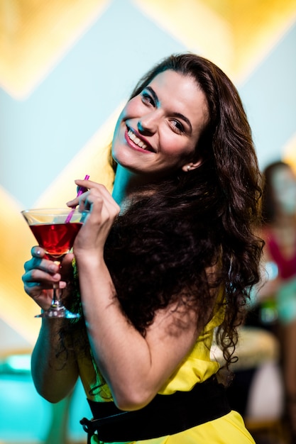 Belle femme ayant un martini rouge