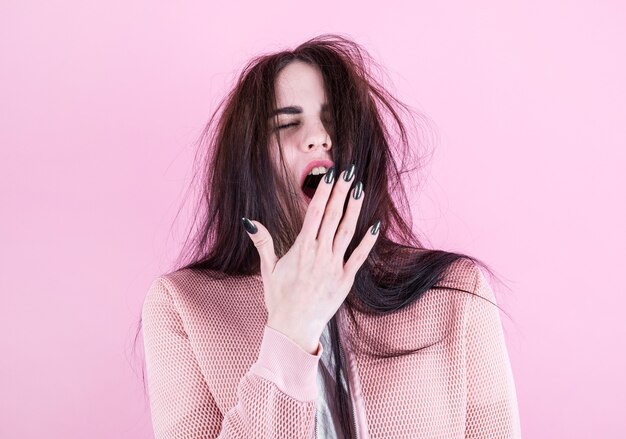 Belle femme béante aux cheveux ébouriffés sur fond rose