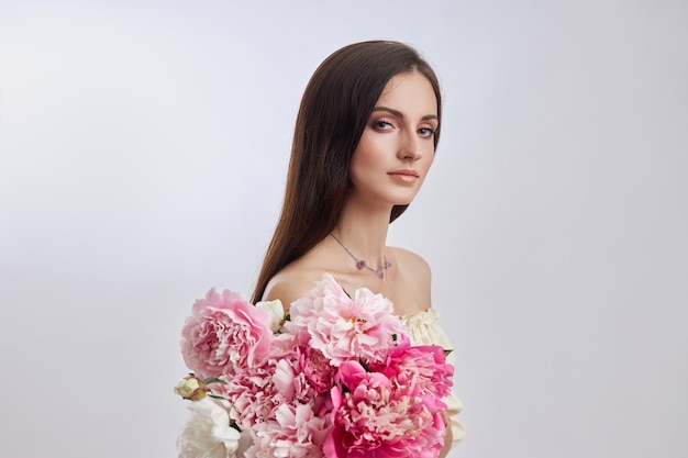 Belle femme avec beaucoup de fleurs roses dans ses mains.