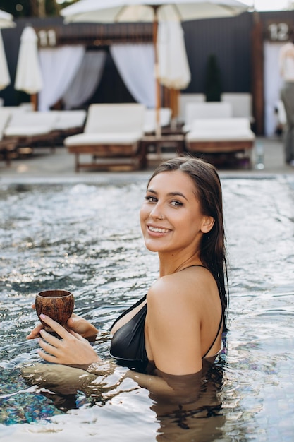 Belle femme en bikini avec cocktail sur fond jacuzzi