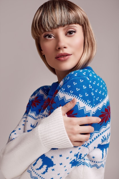 Belle femme blonde aux cheveux courts en pull de Noël