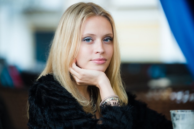 Belle femme blonde aux cheveux longs et maquillage parfait posant au parc automne