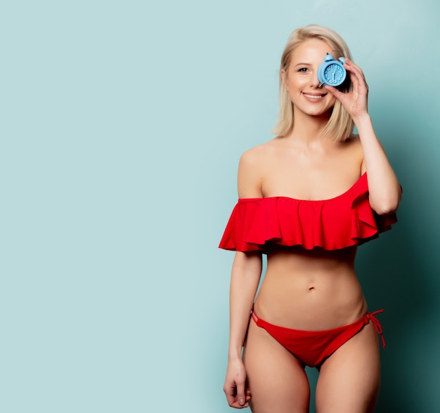 Belle femme blonde en bikini avec petit réveil