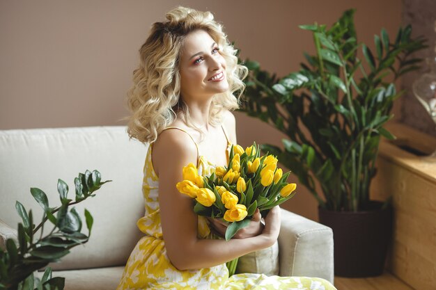 Belle femme blonde avec bouquet de tulipes jaunes