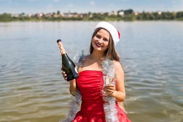 Belle femme blonde avec champagne debout dans l'eau