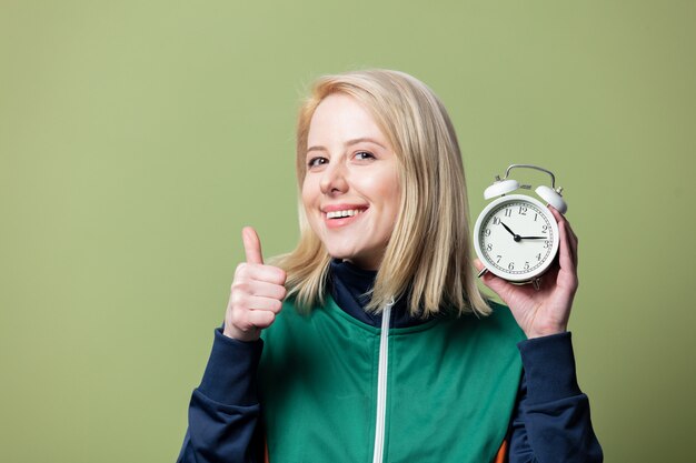 Belle femme blonde en costume de sport des années 90 avec réveil