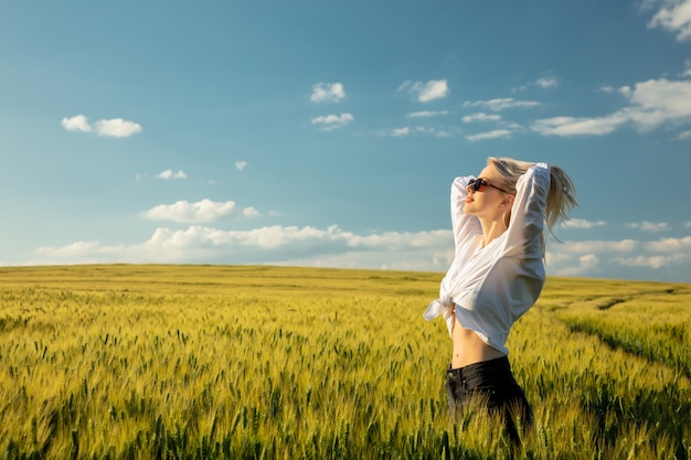 Belle femme blonde dans le champ de blé au coucher du soleil