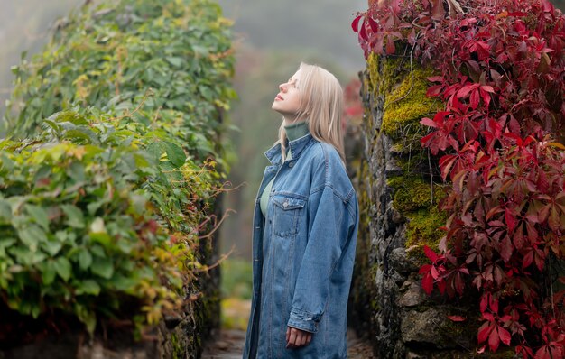 Belle femme blonde dans un jardin avec vigne vierge à l'automne