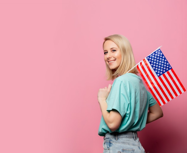 Belle femme blonde avec le drapeau des États-Unis sur le mur rose