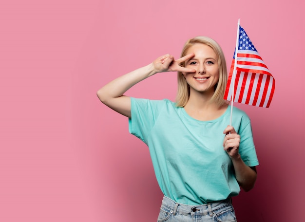 Belle femme blonde avec le drapeau des États-Unis sur le mur rose