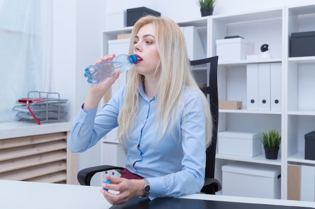 Belle femme blonde eau potable alors qu'il était assis à table