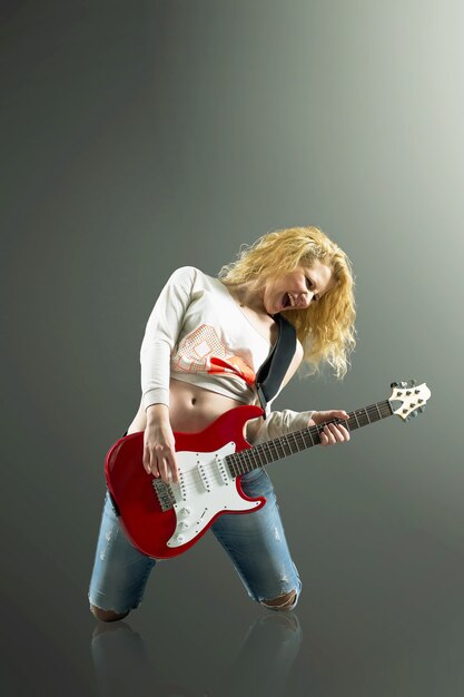 Belle femme blonde avec une guitare chante une chanson rock