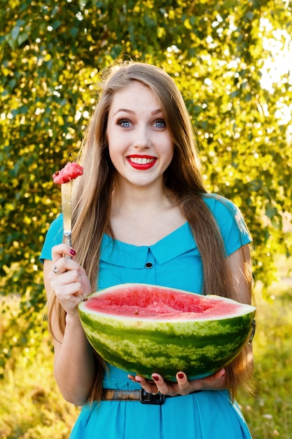 Belle femme blonde mange une pastèque à l'extérieur